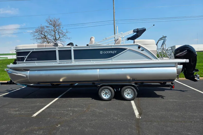 Slide: The Image of 2025 Godfrey Sweetwater 2286 QS pontoon boat on trailer in parking lot. - 4