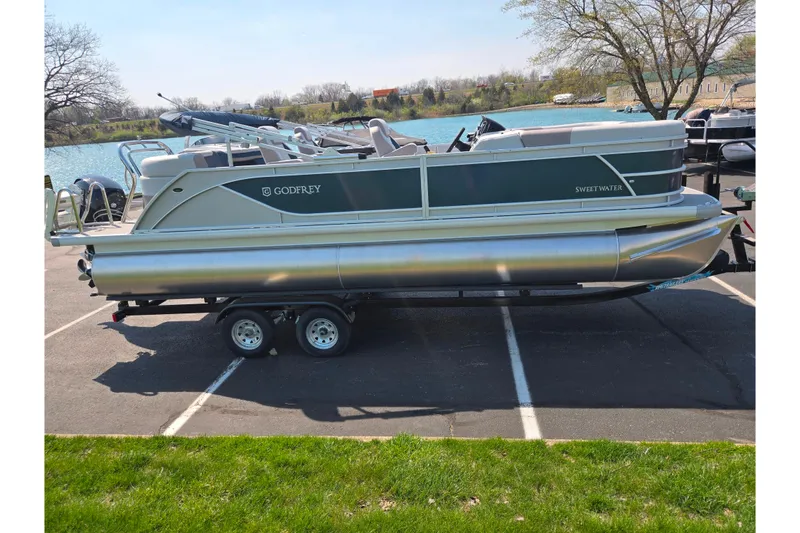 Slide: The Image of 2025 Godfrey Sweetwater 2286 QS pontoon boat on trailer by a lake. - 9