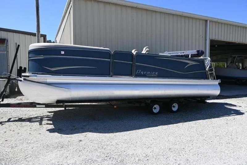The Image of 2020 Premier 230 Sunsation RL - CL pontoon boat on trailer, parked outside a metal building. - 0
