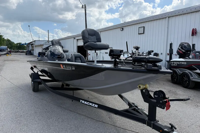 The Image of 2020 Tracker Pro Team 190 TX boat on trailer, parked outside a warehouse under cloudy sky. - 2