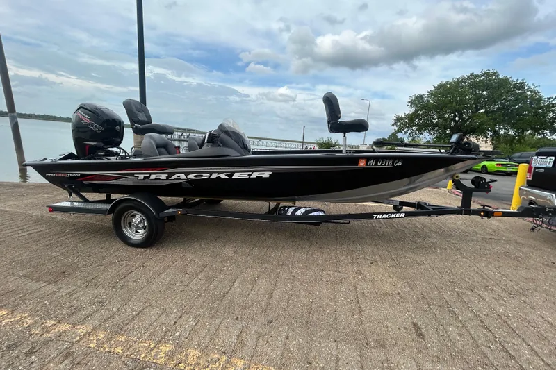 Slide: The Image of 2020 Tracker Pro Team 190 TX boat on trailer, parked near a lake under cloudy skies. - 52