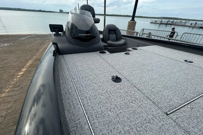 Slide: The Image of 2020 Tracker Pro Team 190 TX boat at a lakeside dock, featuring spacious deck and seating. - 56