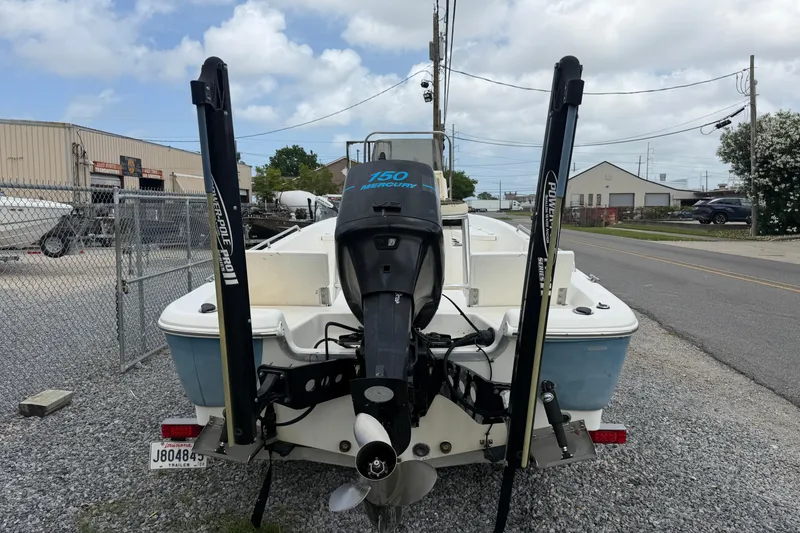 Slide: The Image of 2006 NAUTIC STAR 2100 boat with Mercury 150 engine, parked on gravel near industrial area. - 4