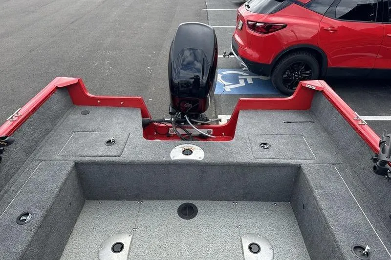 Slide: The Image of 2017 Tracker Pro Guide V-16 SC boat interior with motor, parked near a red car. - 14