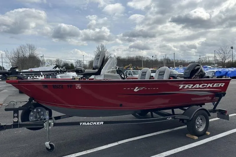 Slide: The Image of 2017 Tracker Pro Guide V-16 SC boat on trailer, parked outdoors under cloudy sky. - 16
