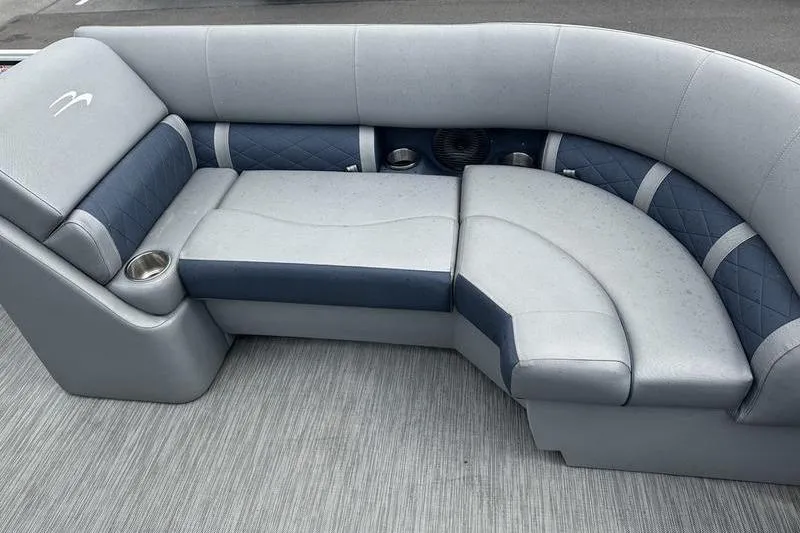 Slide: The Image of 2022 Bennington L 23 L-Bench boat seating with gray and blue upholstery, featuring cup holders. - 6