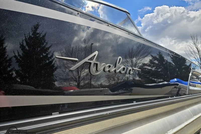 Slide: The Image of 2024 Avalon Excalibur Quad Lounge boat with sleek black exterior and reflective finish. - 11