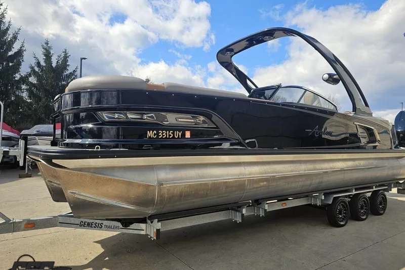 Slide: The Image of 2024 Avalon Excalibur Quad Lounge Windshield boat on trailer, sleek design, parked outdoors. - 24