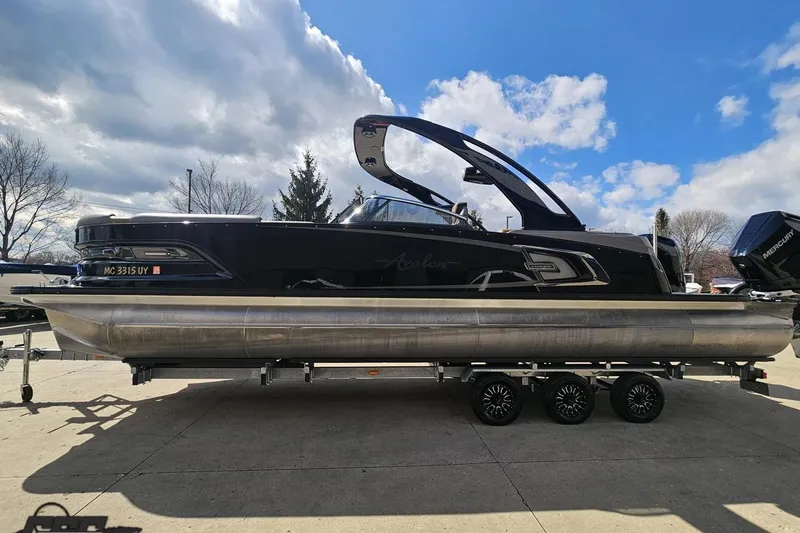 Slide: The Image of 2024 Avalon Excalibur Quad Lounge Windshield pontoon boat on trailer under blue sky. - 25