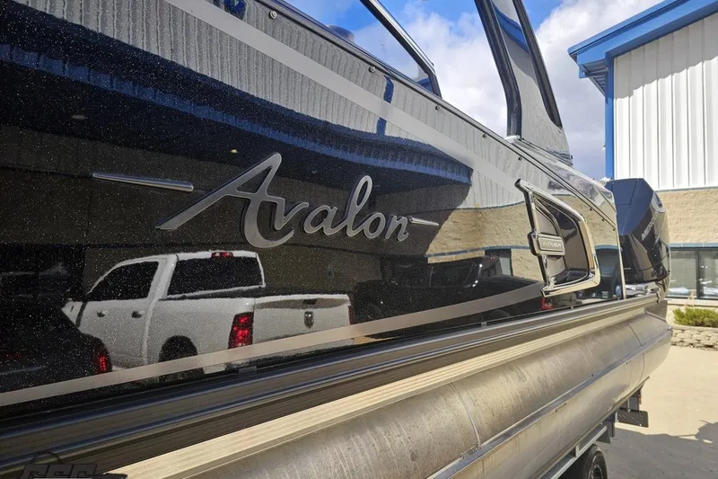 Slide: The Image of 2024 Avalon Excalibur Quad Lounge Windshield boat, sleek design, parked outdoors. - 31