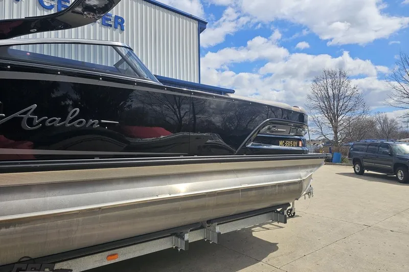 Slide: The Image of 2024 Avalon Excalibur Quad Lounge boat at a marina, under a partly cloudy sky. - 5