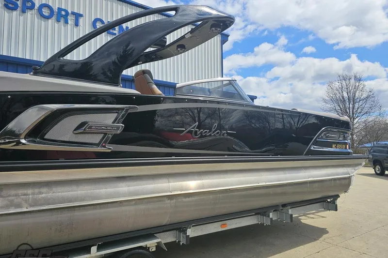Slide: The Image of 2024 Avalon Excalibur Quad Lounge Windshield boat displayed outdoors. - 6