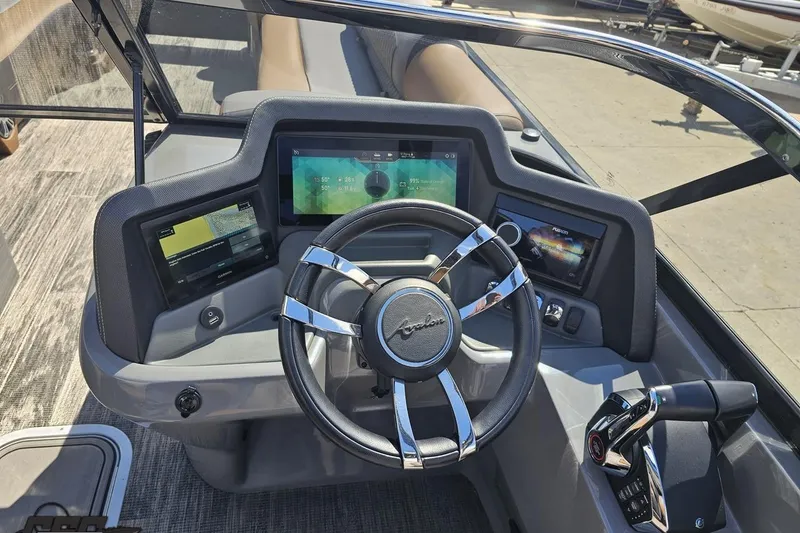 Slide: The Image of 2024 Avalon Excalibur Quad Lounge boat dashboard with modern controls and sleek steering wheel. - 81