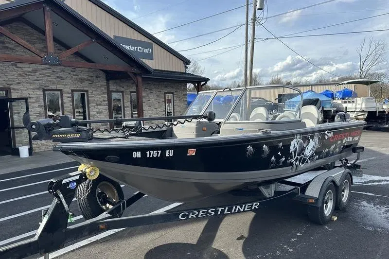 Slide: The Image of 2011 Crestliner 1850 Fish Hawk SC boat on trailer, parked outside a building. - 1