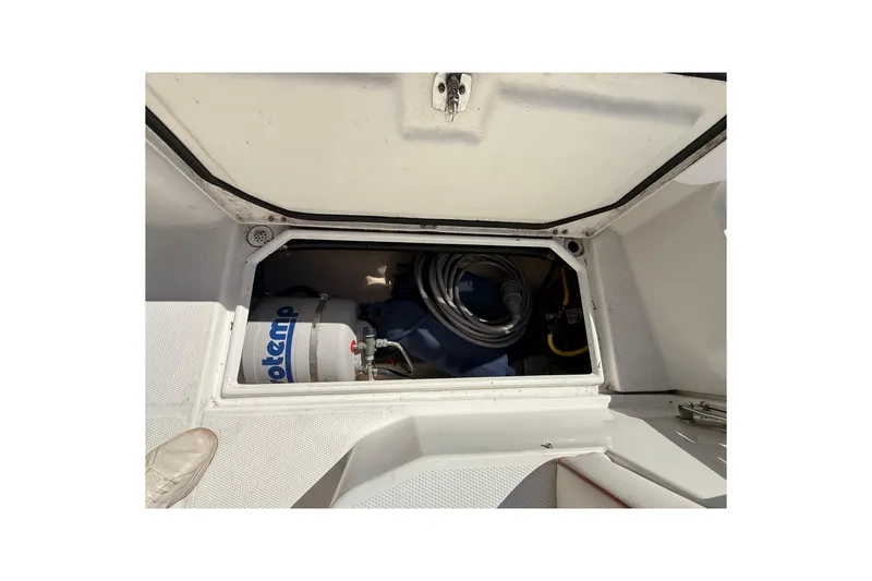 Slide: The Image of Storage compartment of a 2016 Cutwater 24 boat, featuring a water heater and hoses. - 11