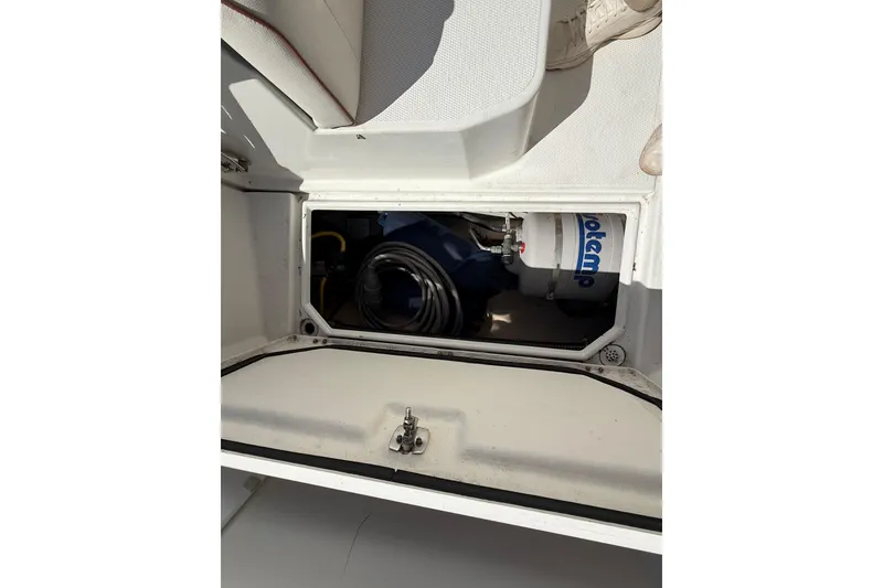 Slide: The Image of Storage compartment in a 2016 Cutwater 24 boat, featuring a water heater and coiled hose. - 12