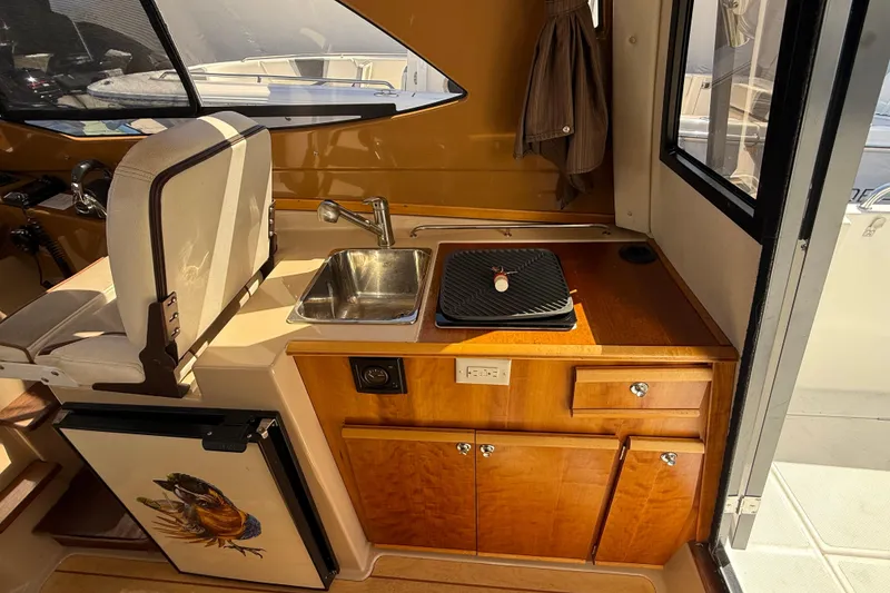 Slide: The Image of Interior of a 2016 Cutwater 24 boat featuring a compact kitchen area. - 22