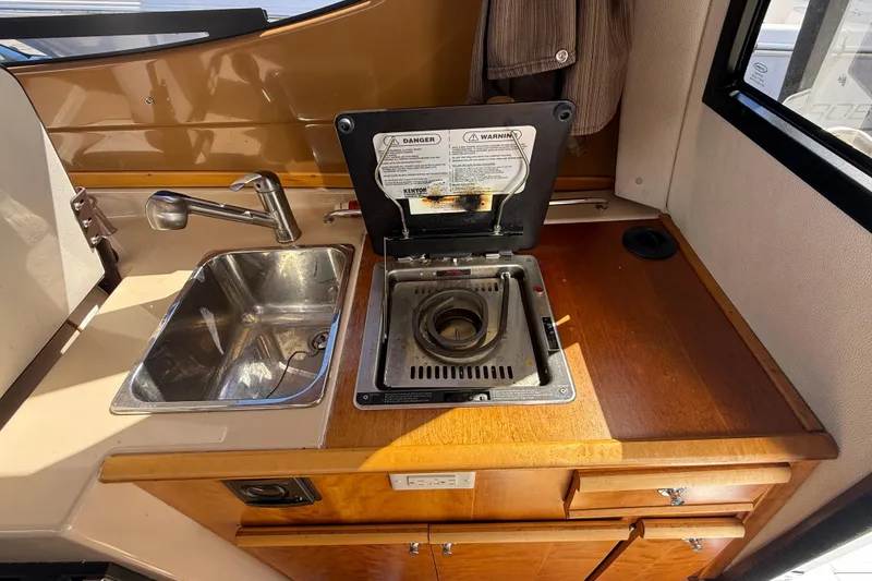 Slide: The Image of Compact kitchen area in a 2016 Cutwater 24 boat with sink and stove. - 23