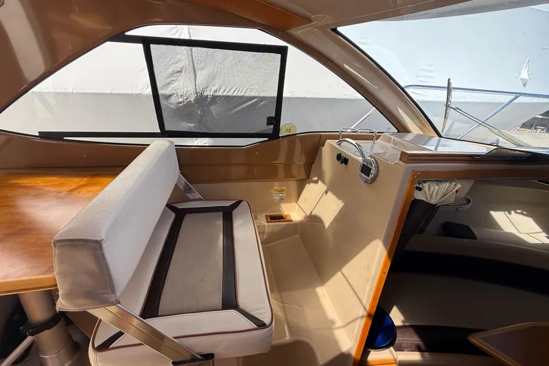 Slide: The Image of Interior of a 2016 Cutwater 24 boat, featuring seating and a wooden table. - 26