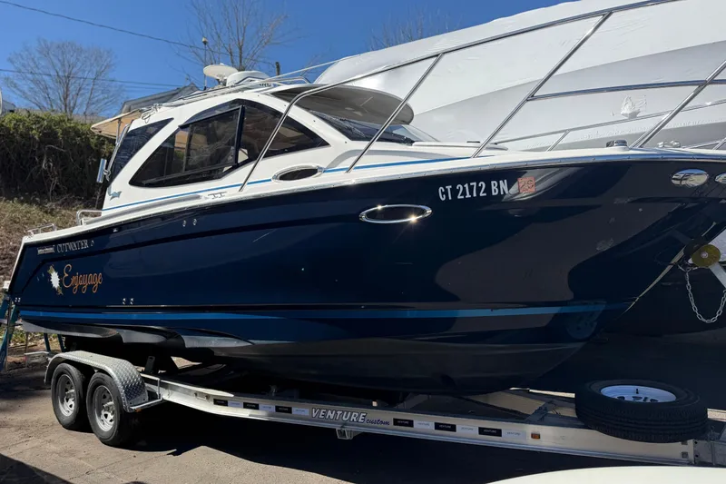 Slide: The Image of 2016 Cutwater 24 boat on trailer, dark blue hull, parked outdoors. - 3