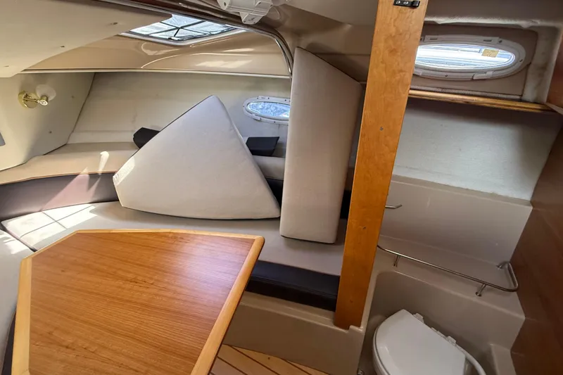 Slide: The Image of Interior of a 2016 Cutwater 24 boat, featuring seating, table, and compact toilet area. - 38