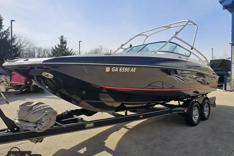 Slide: The Image of 2008 Regal 2520 FasDeck boat on trailer, black hull, parked outdoors. - 24