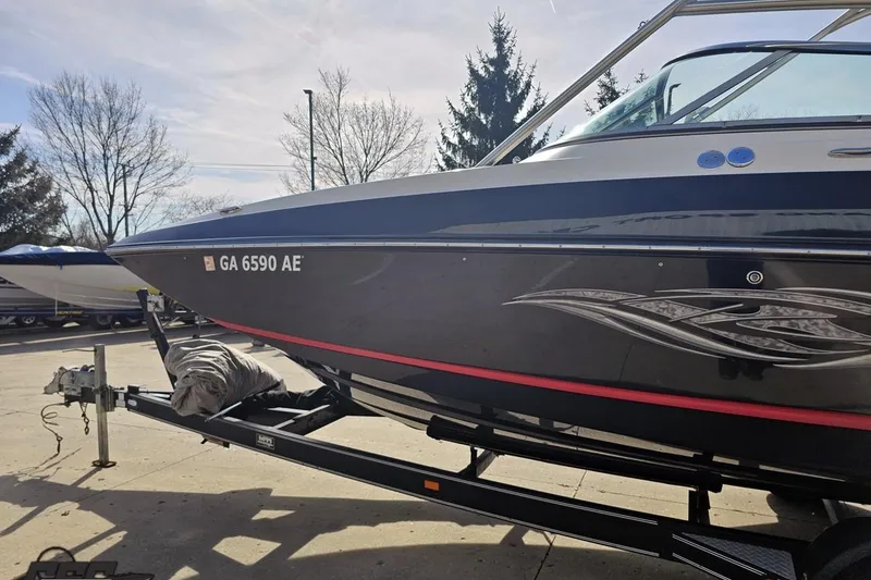 Slide: The Image of 2008 Regal 2520 FasDeck boat on trailer, parked outdoors, with decorative graphics. - 26