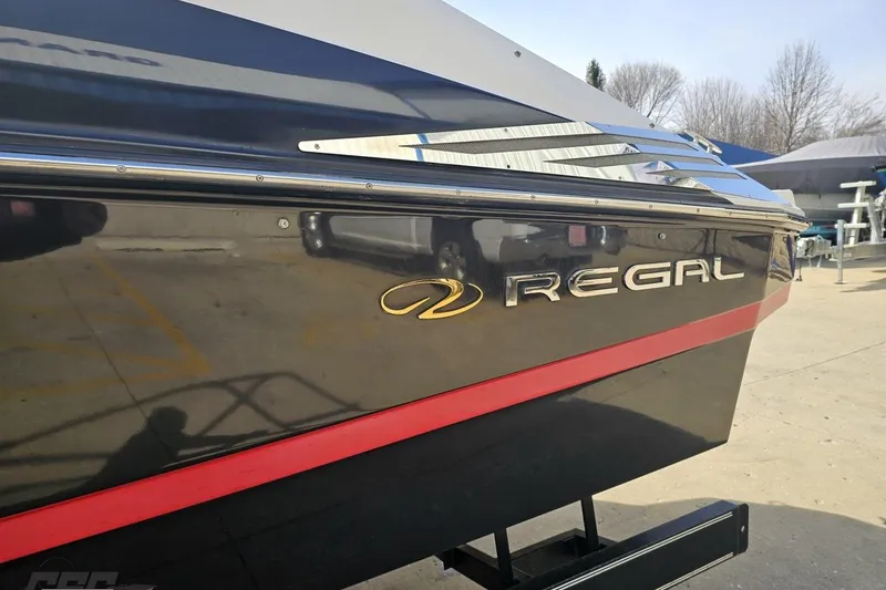 Slide: The Image of 2008 Regal 2520 FasDeck boat with sleek black and red design, parked outdoors. - 28