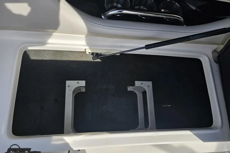 Slide: The Image of Storage compartment in a 2008 Regal 2520 FasDeck boat, featuring metal brackets and hydraulic support. - 61