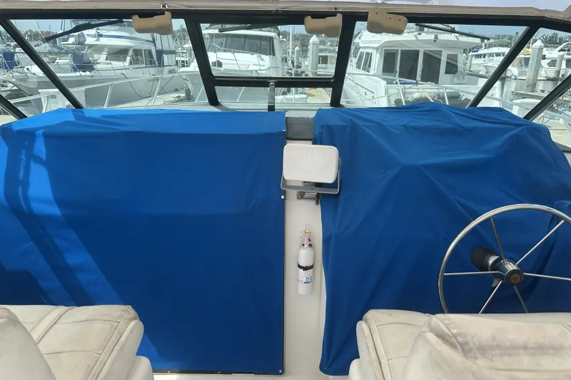 Slide: The Image of 1990 Tiara Yachts 3600 Open cockpit with blue covers and steering wheel at marina. - 11