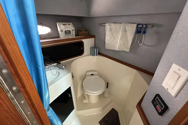 Slide: The Image of 1990 Tiara Yachts 3600 Open bathroom with toilet, sink, and storage. - 16