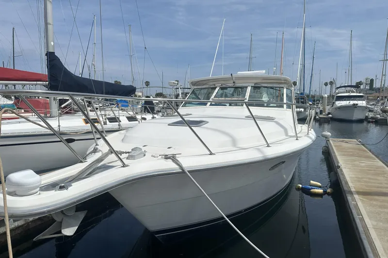 Slide: The Image of 1990 Tiara Yachts 3600 Open docked at marina, surrounded by sailboats. - 4