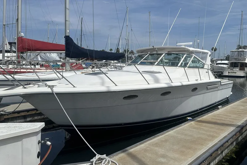 Slide: The Image of 1990 Tiara Yachts 3600 Open docked at marina, surrounded by sailboats. - 5