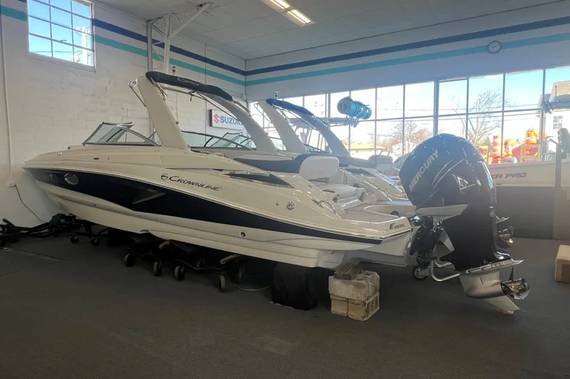 Slide: The Image of 2024 Crownline Eclipse E290 XS boat displayed indoors with Mercury outboard motor. - 5
