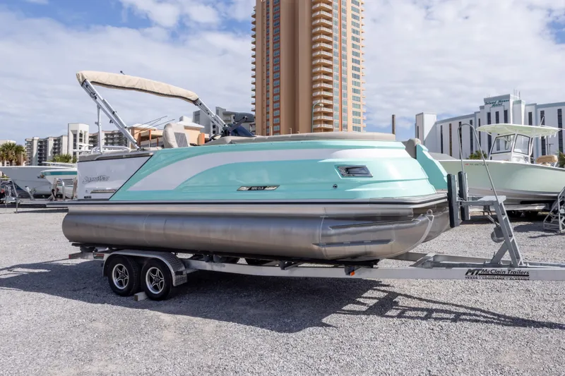 Slide: The Image of 2024 SilverWave 2210 CLS SW5 pontoon boat on trailer, with buildings in background. - 2