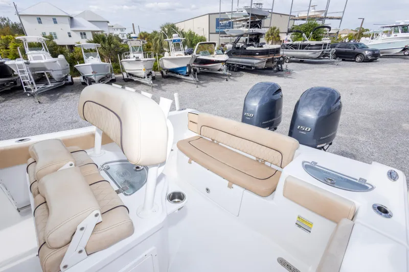 Slide: The Image of 2019 Sportsman Heritage 251 Center Console boat with dual engines, beige seating, and marina background. - 26