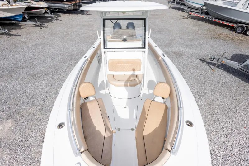 Slide: The Image of 2019 Sportsman Heritage 251 Center Console boat with beige seating, parked on gravel. - 35