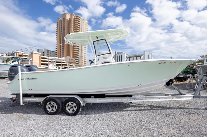 Slide: The Image of 2019 Sportsman Heritage 251 Center Console boat on trailer, urban backdrop, partly cloudy sky. - 4