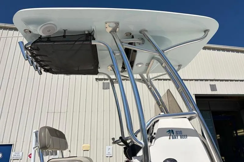 Slide: The Image of 2024 Key West 210 Bay Reef boat with T-top and storage, docked near a building. - 17