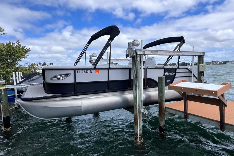 The Image of 2023 Bentley Pontoons 250 Elite Admiral docked on a lift by the water. - 0