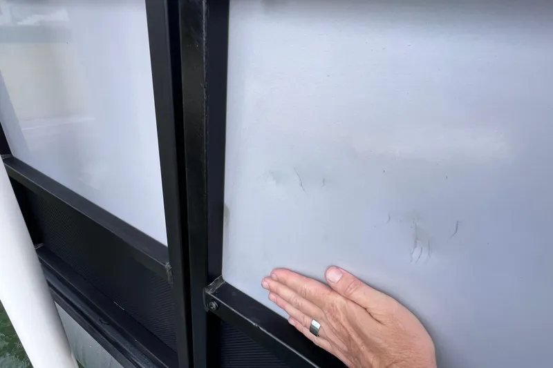 Slide: The Image of Close-up of a hand inspecting the 2023 Bentley Pontoons 250 Elite Admiral exterior panel. - 51