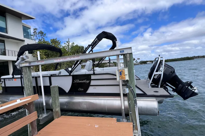 Slide: The Image of 2023 Bentley Pontoons 250 Elite Admiral on a boat lift by the water. - 6