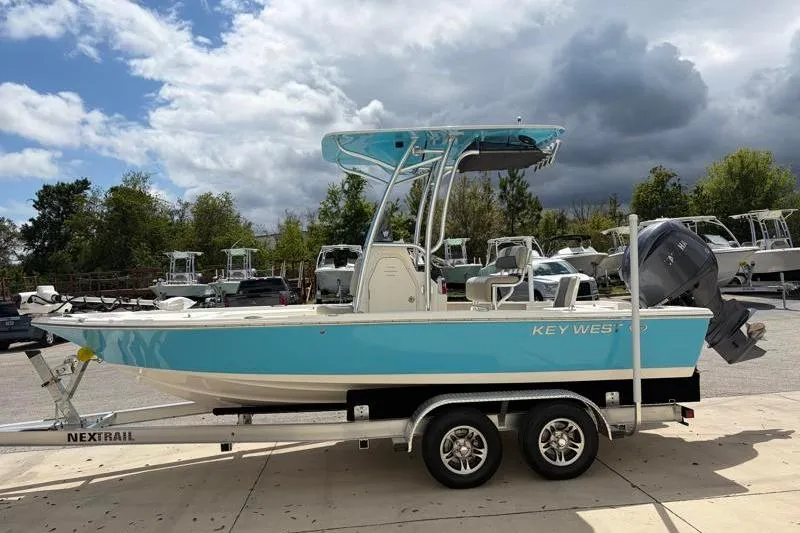Slide: The Image of 2025 Key West 210 Bay Reef boat on trailer, parked outdoors under cloudy sky. - 4