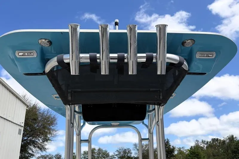Slide: The Image of 2025 Key West 210 Bay Reef boat with blue T-top and rod holders against a cloudy sky. - 45
