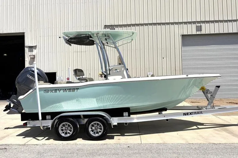 Slide: The Image of 2024 Key West 203 FS boat on trailer, parked outside industrial building. - 1