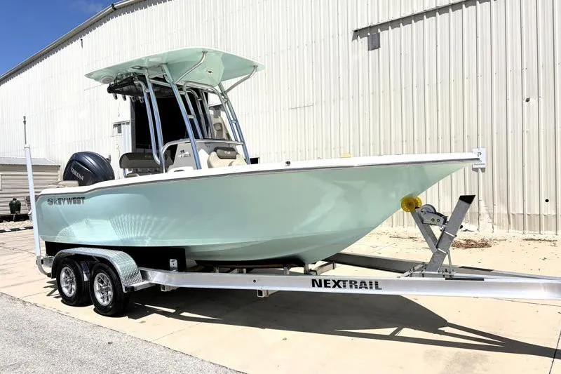 Slide: The Image of 2024 Key West 203 FS boat on trailer, parked near a large building. - 2