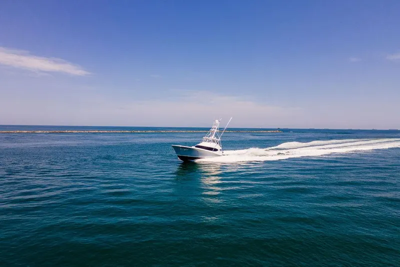 Slide: The Image of Hatteras 63 GT 2014 yacht cruising on open blue sea under clear sky. - 10