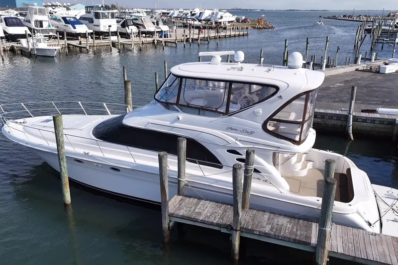Slide: The Image of 2001 Sea Ray 560 Sedan Bridge yacht docked at marina, surrounded by other boats. - 2