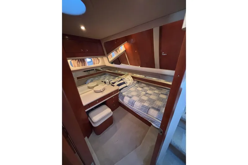 Slide: The Image of Interior cabin of 2001 Sea Ray 560 Sedan Bridge yacht, featuring cozy bed and wooden cabinetry. - 24