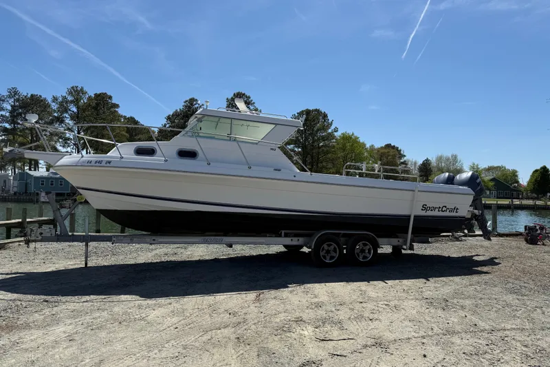 Slide: The Image of 2007 Sport-Craft 302 Sport Fish boat on trailer by waterfront, clear sky background. - 2